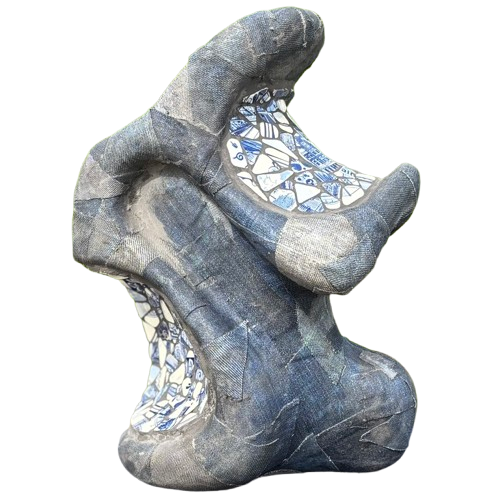 Abstracte grijze sculptuur met witte mozaïekaccenten en een open, organische vorm.