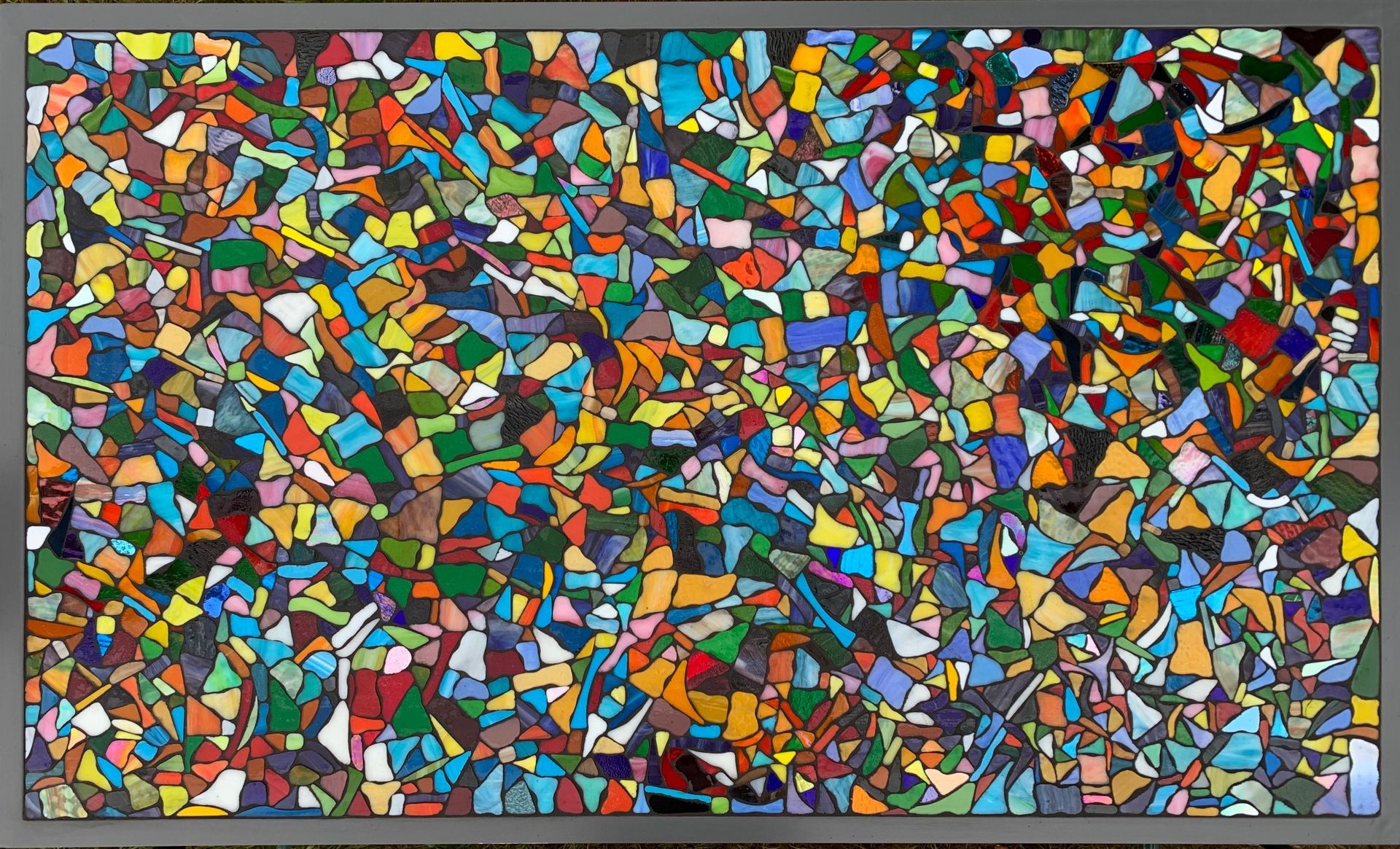 Abstracte mozaïek van kleurrijke geometrische vormen die het kader vullen, met een grijze rand eromheen.