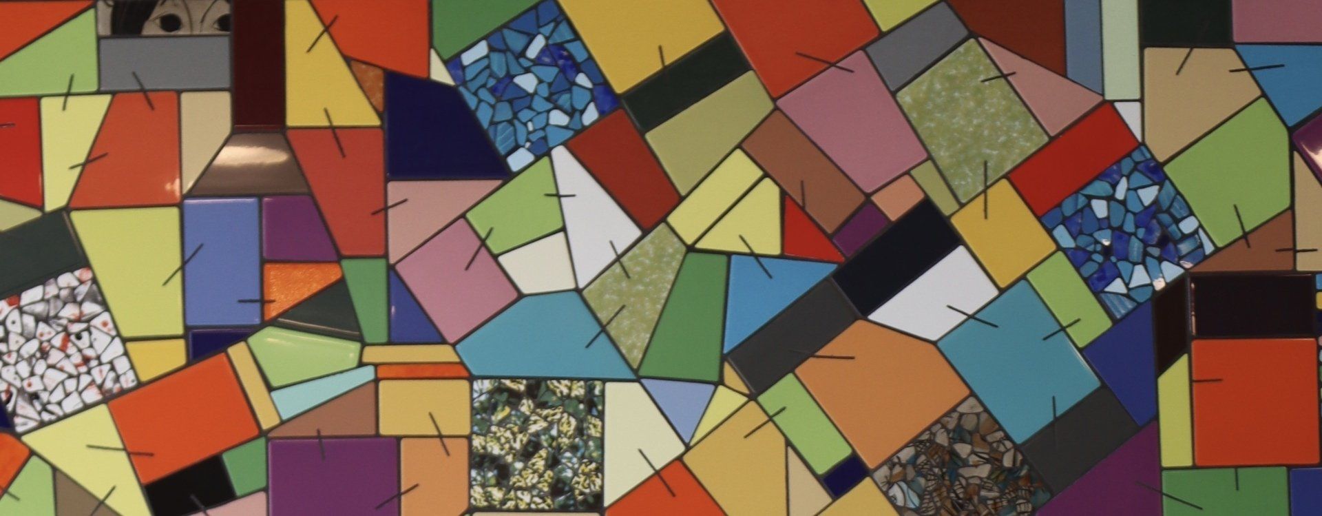 Abstracte mozaïek van veelkleurige geometrische tegels en driehoeken in rood, blauw, groen, geel en grijs.