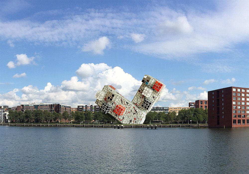 Omgevallen witte kubussculptuur aan het water, vlakbij bakstenen gebouwen, onder een bewolkte hemel.