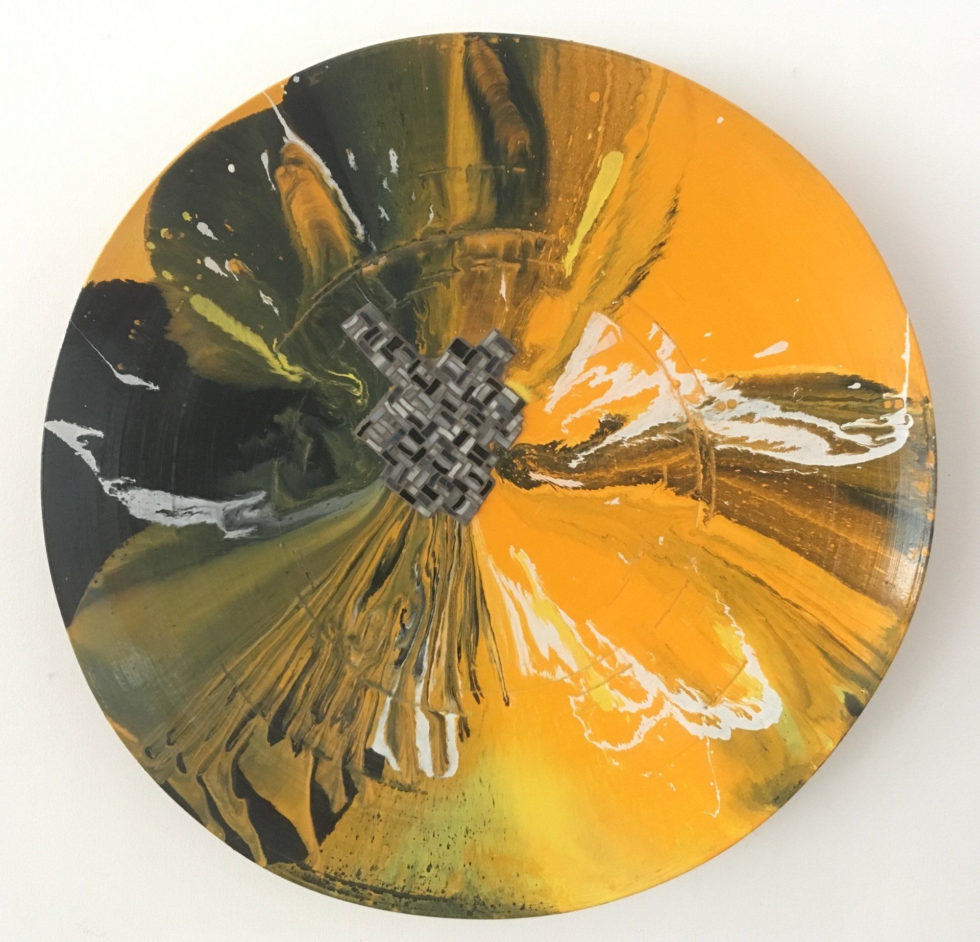 Abstract cirkelvormig kunstwerk van goud en zwart metaal met een gestructureerd middenstuk en reflecterende plooien.