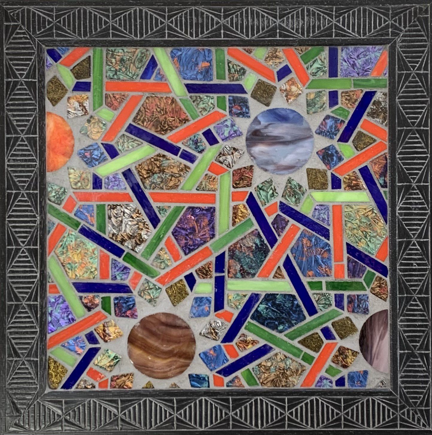 Abstracte mozaïek met kleurrijke geometrische scherven en cirkelvormige, planeetachtige figuren.