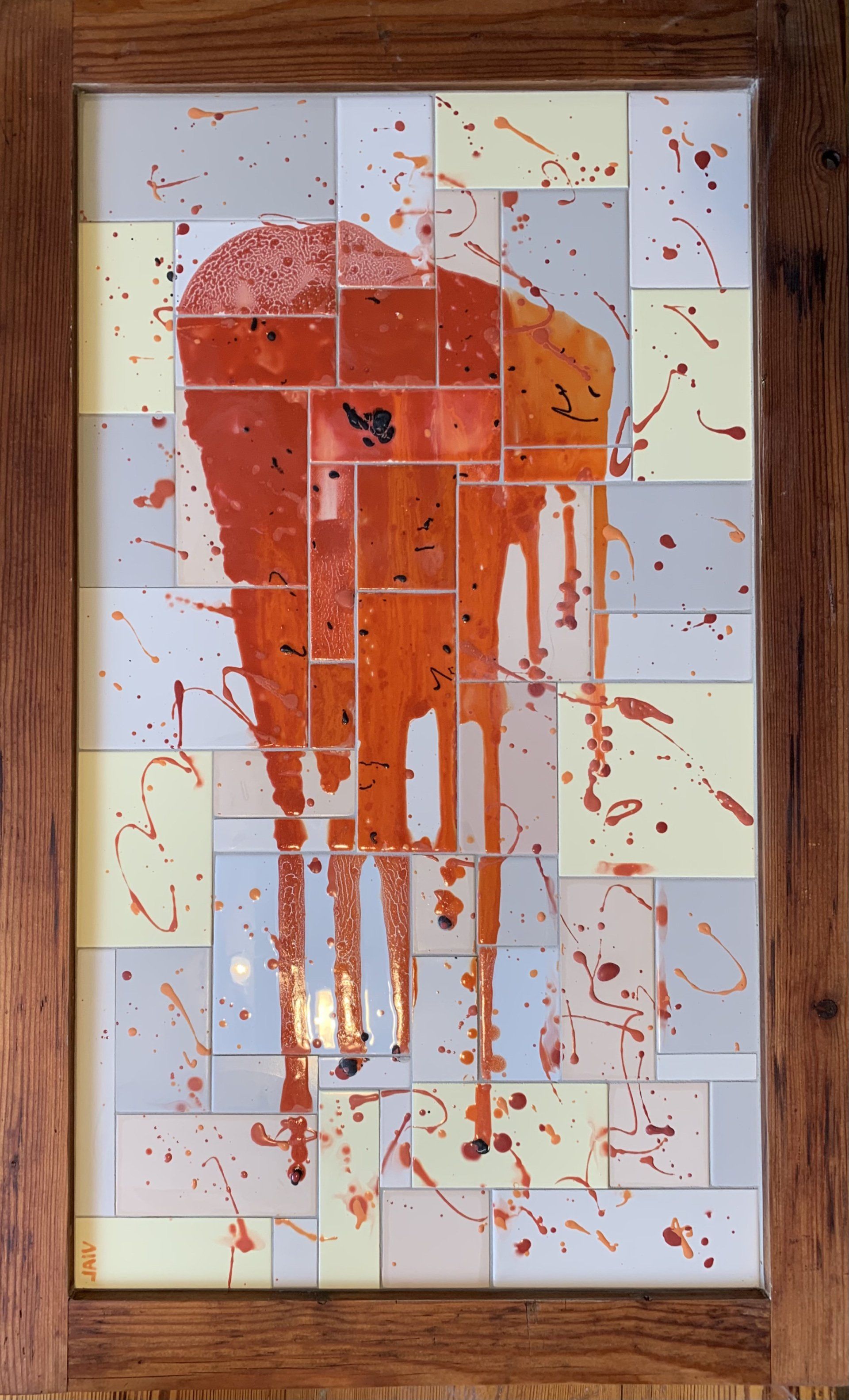 Abstracte oranje en rode verfspatten op een betegeld wandpaneel met een houten frame.