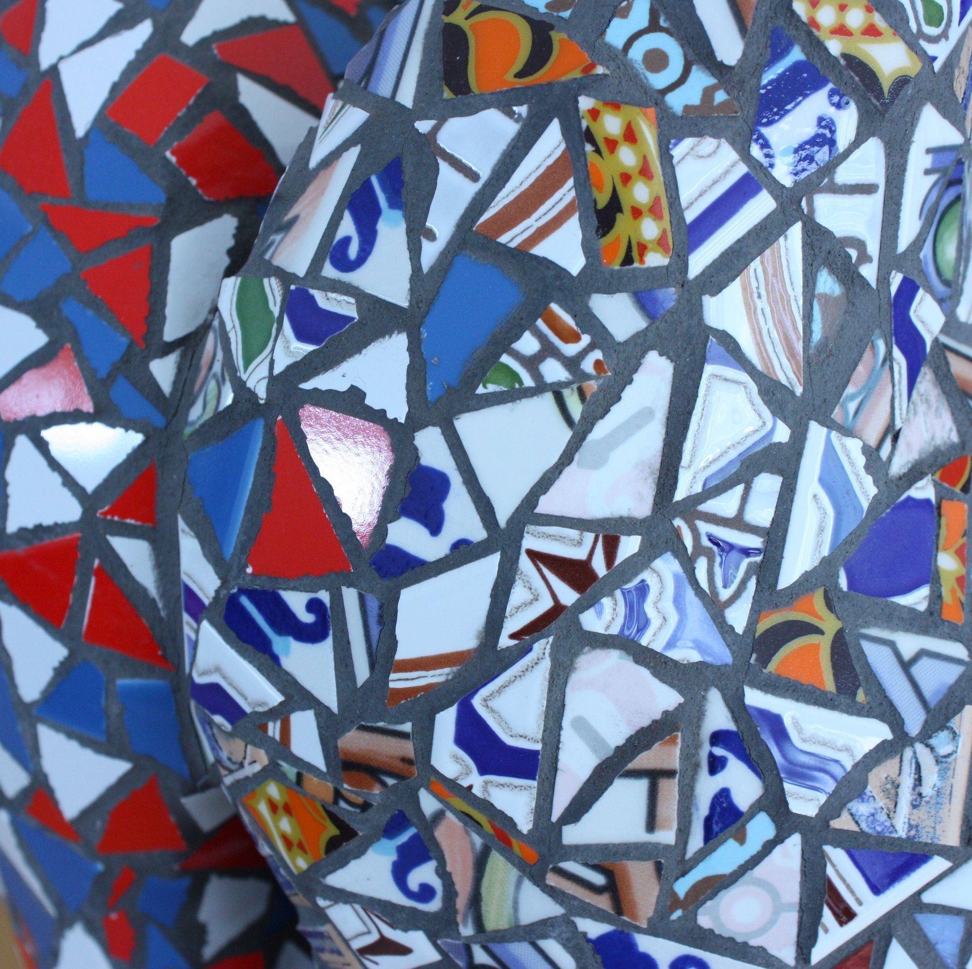 Kleurrijk abstract mozaïek van gebroken glasachtige vormen in blauw, rood, wit en oranje.