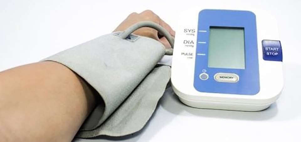 Bracciale per la misurazione della pressione sanguigna sul braccio di una persona accanto a un monitor digitale che visualizza una lettura
