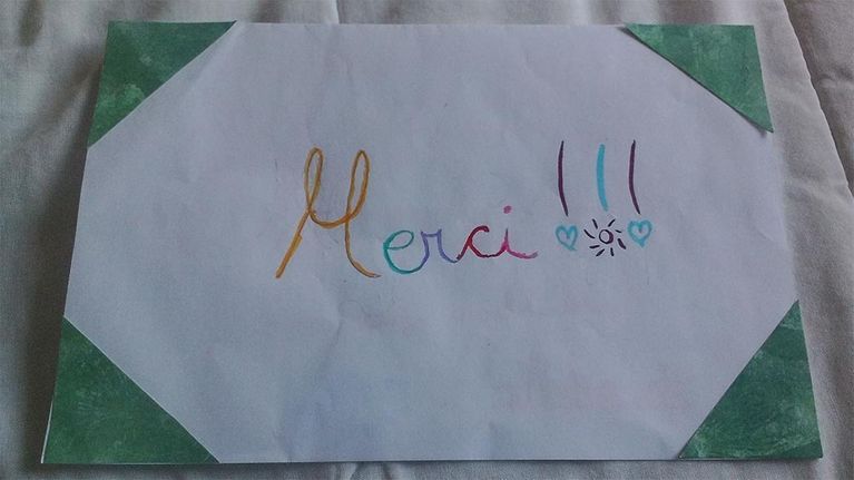 Carte blanche avec l'inscription « Merci !!! » en lettres colorées et des coins verts.