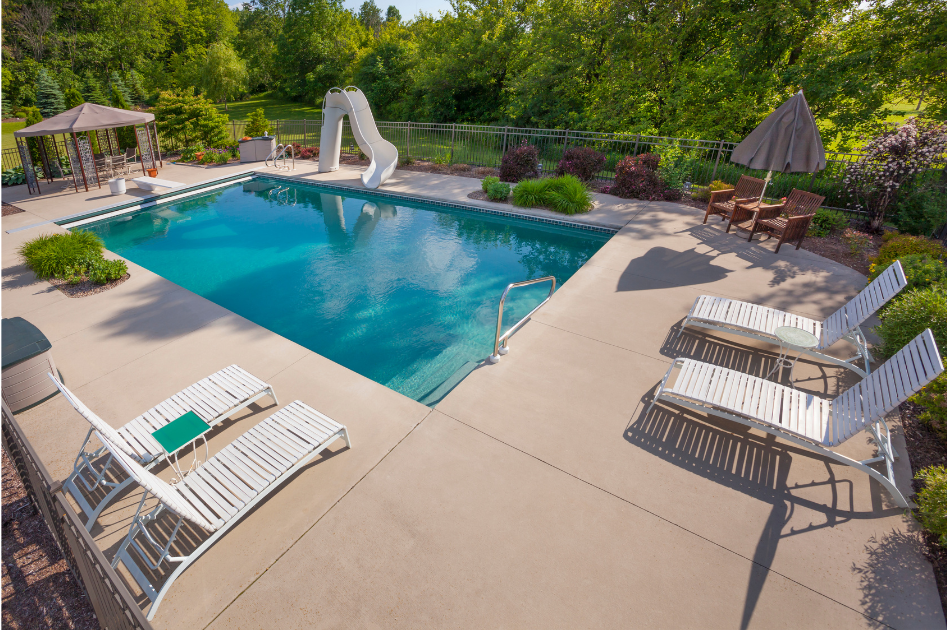 Swimming pool with a wooden pergola, surrounded by grass and a concrete patio.
