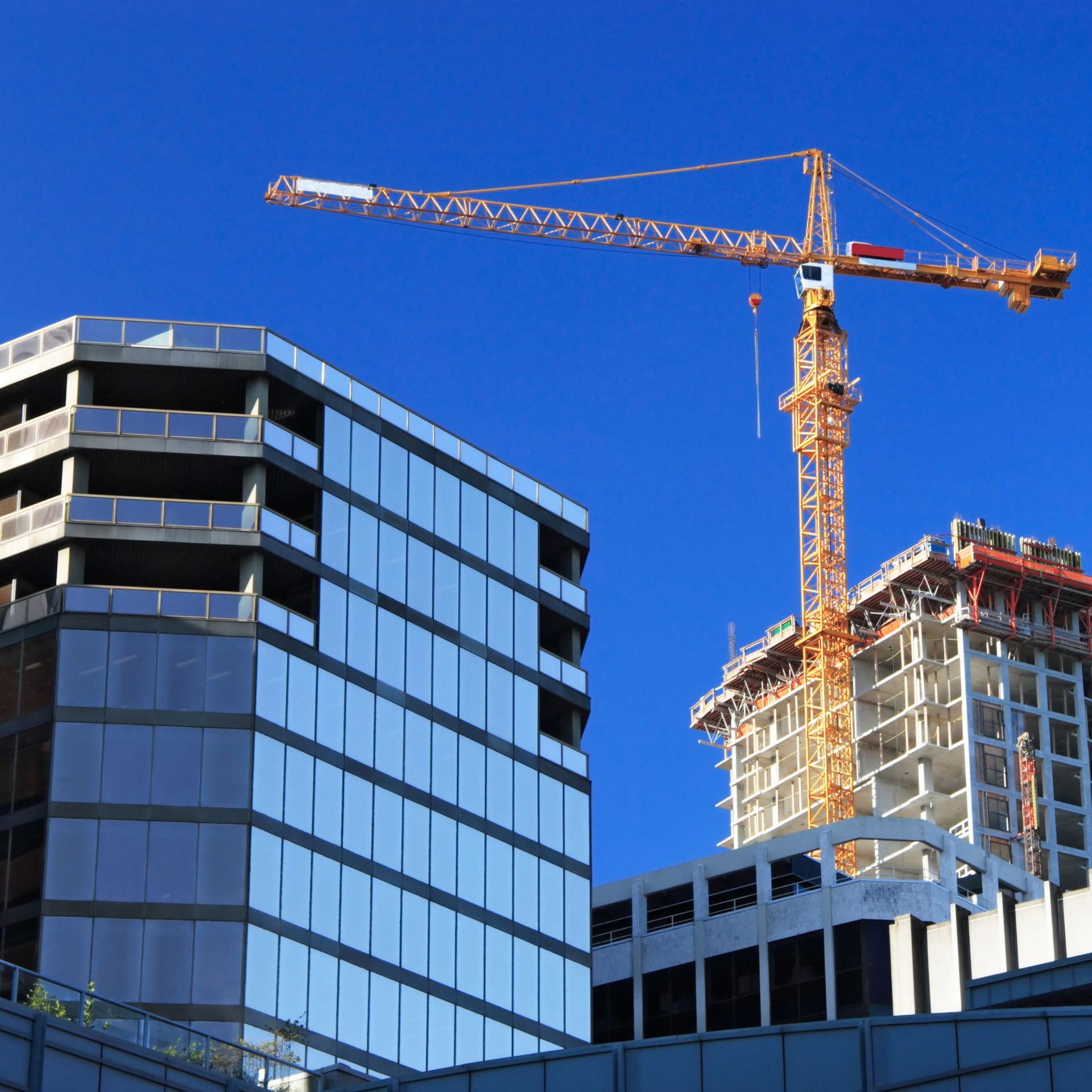 Construction site with buildings, a crane, and a clear blue sky.
