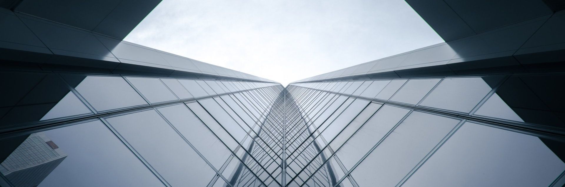 Looking up at two tall glass skyscrapers. A chain links them, and the sky peeks through.