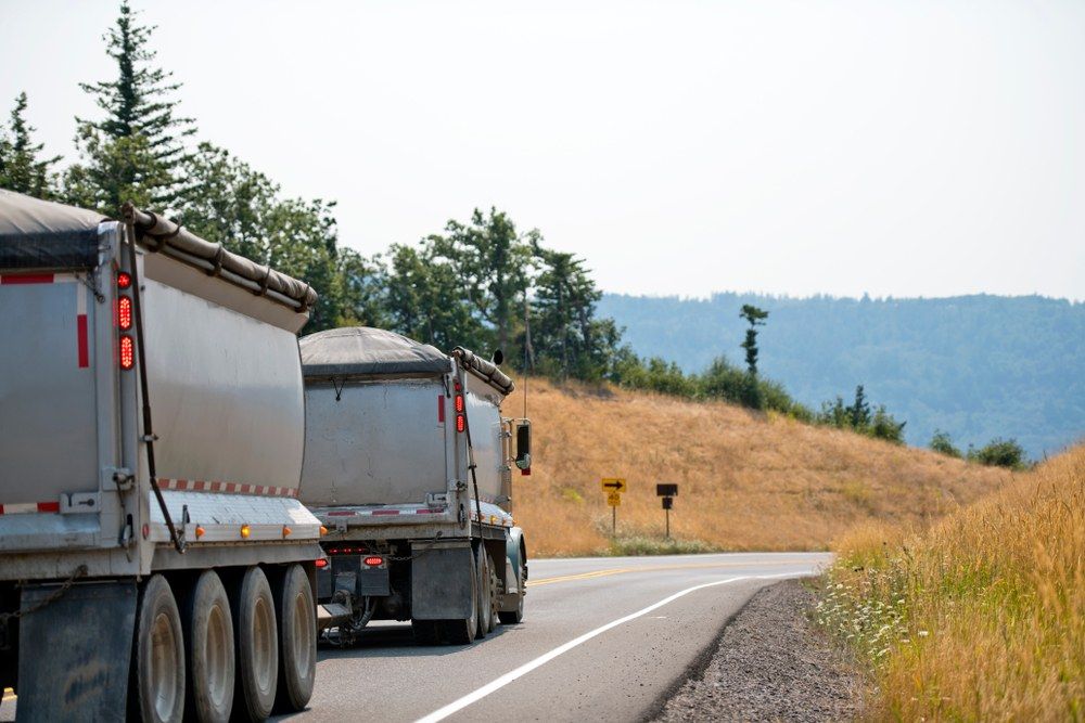 A Couple of Trucks Are Driving Down a Road — Jammach Earthmoving in Maitland, NSW