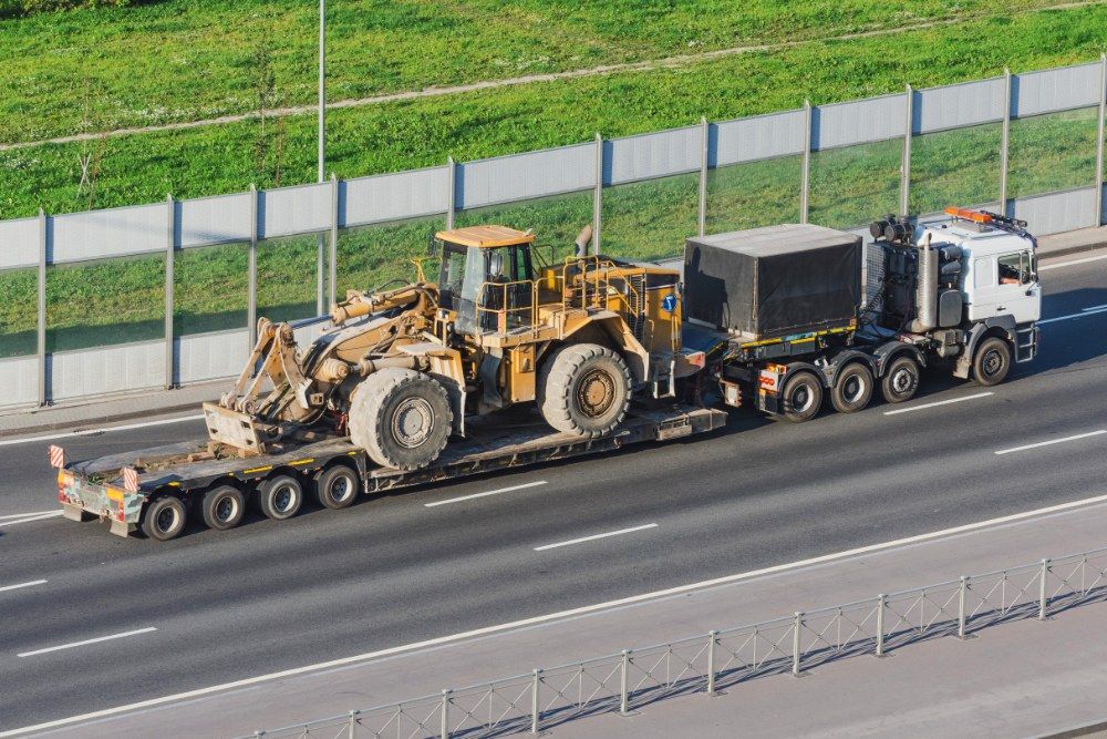 A Truck is Carrying a Bulldozer on a Trailer on a Highway — Jammach Earthmoving in Maitland, NSW