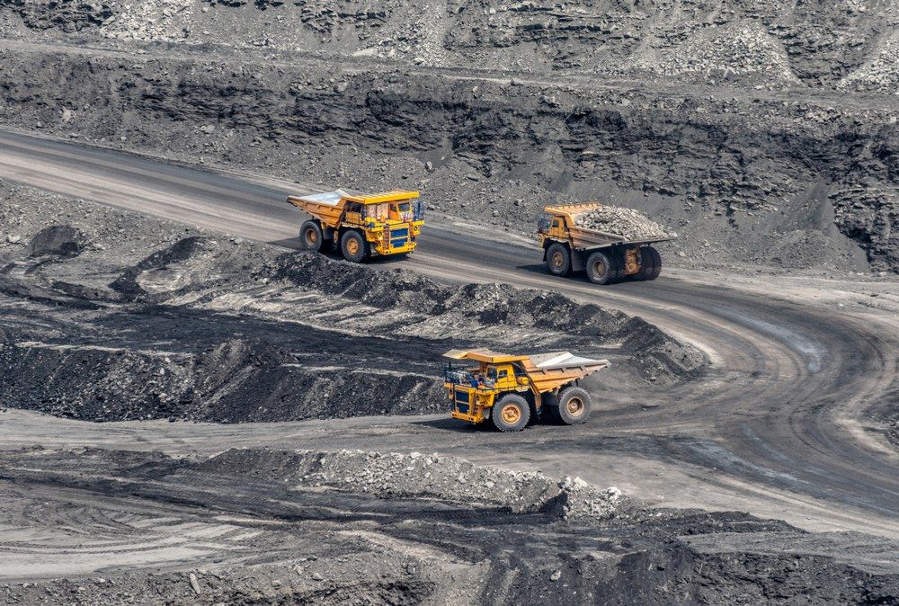 Two Trucks Are Driving Down a Dirt Road — Jammach Earthmoving in Mid North Coast, NSW