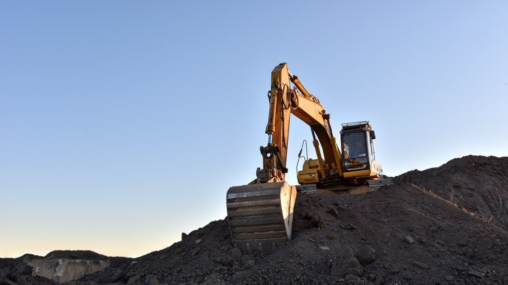 A Yellow Excavator is Sitting on Top of a Pile of Dirt — Jammach Earthmoving in Newcastle, NSW