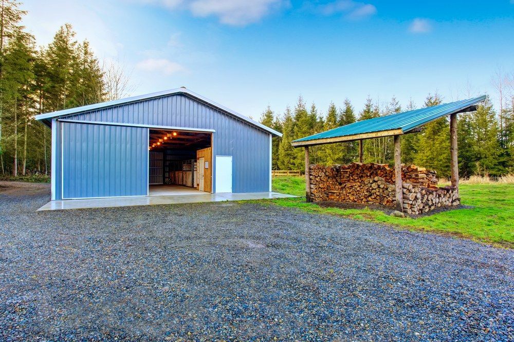 A Blue Metal Barn and a Gravel Road in Front of It — Jammach Earthmoving in Muswellbrook, NSW