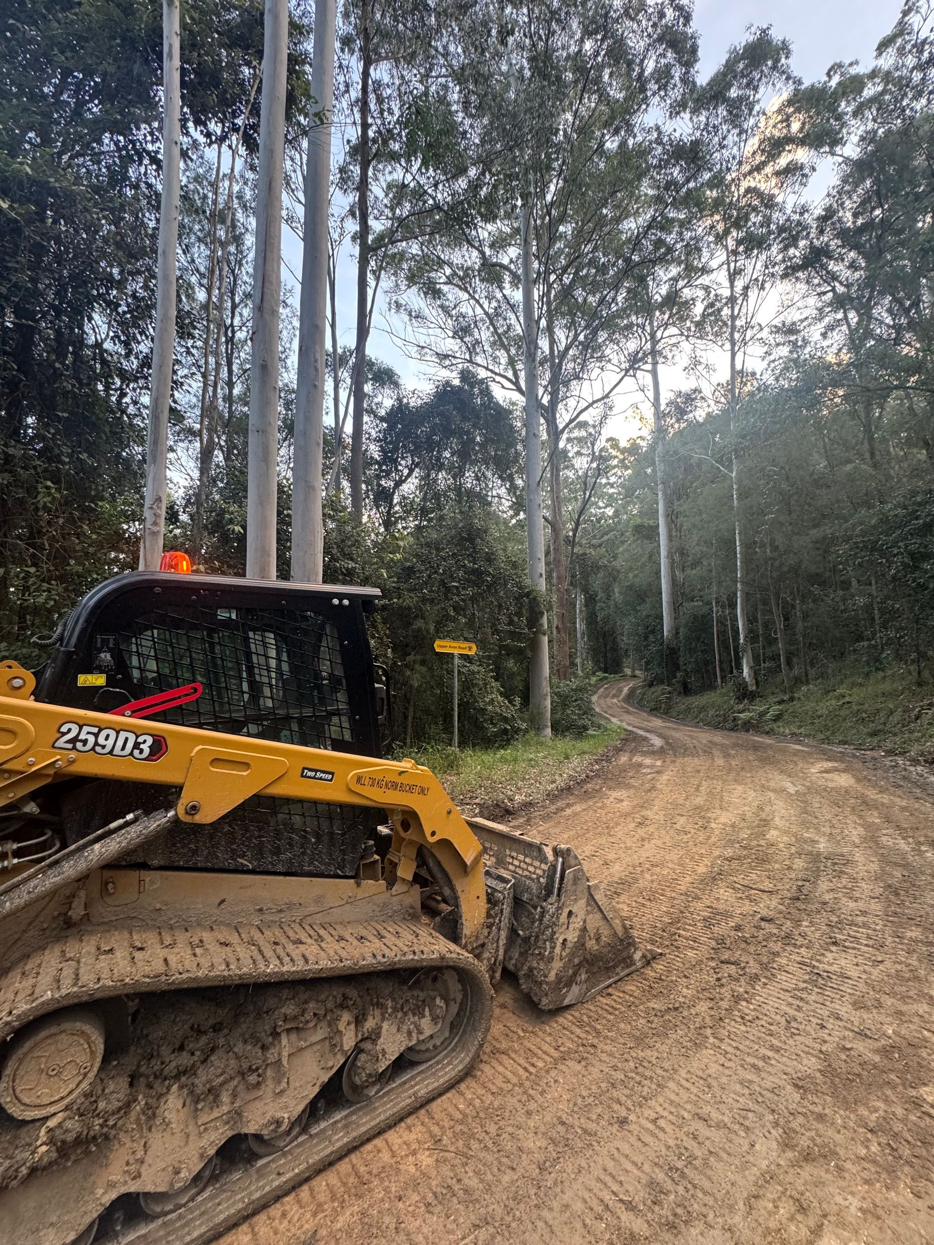 A Bulldozer is Driving Down a Dirt Road in the Woods — Jammach Earthmoving in Nulkaba, NSW