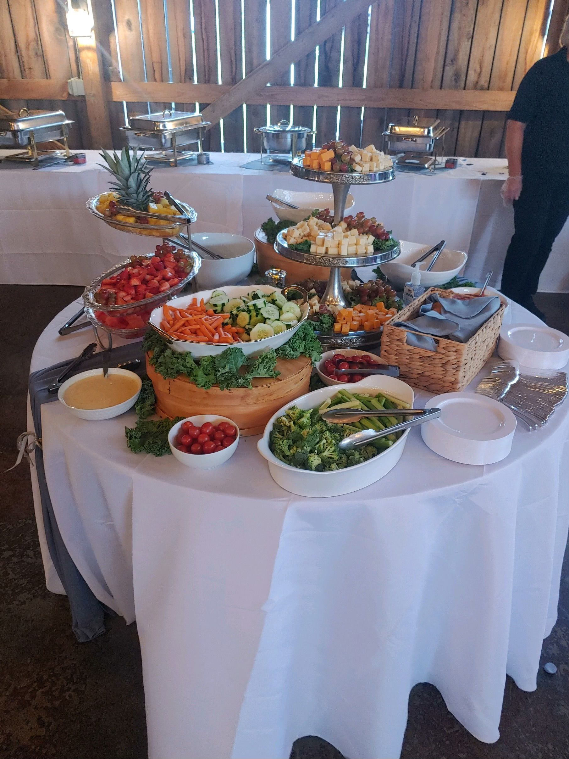 Buffet table with salad bar at an event in a rustic venue. Bowls of salads, toppings, and dressings are arranged on a table.