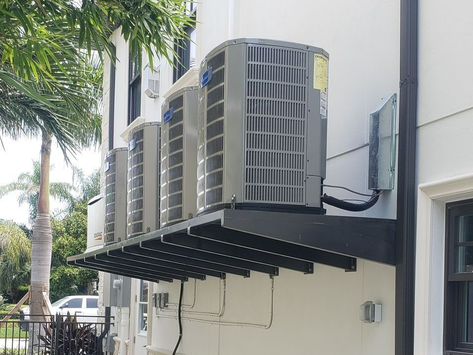 Two air conditioners are sitting on the side of a house.