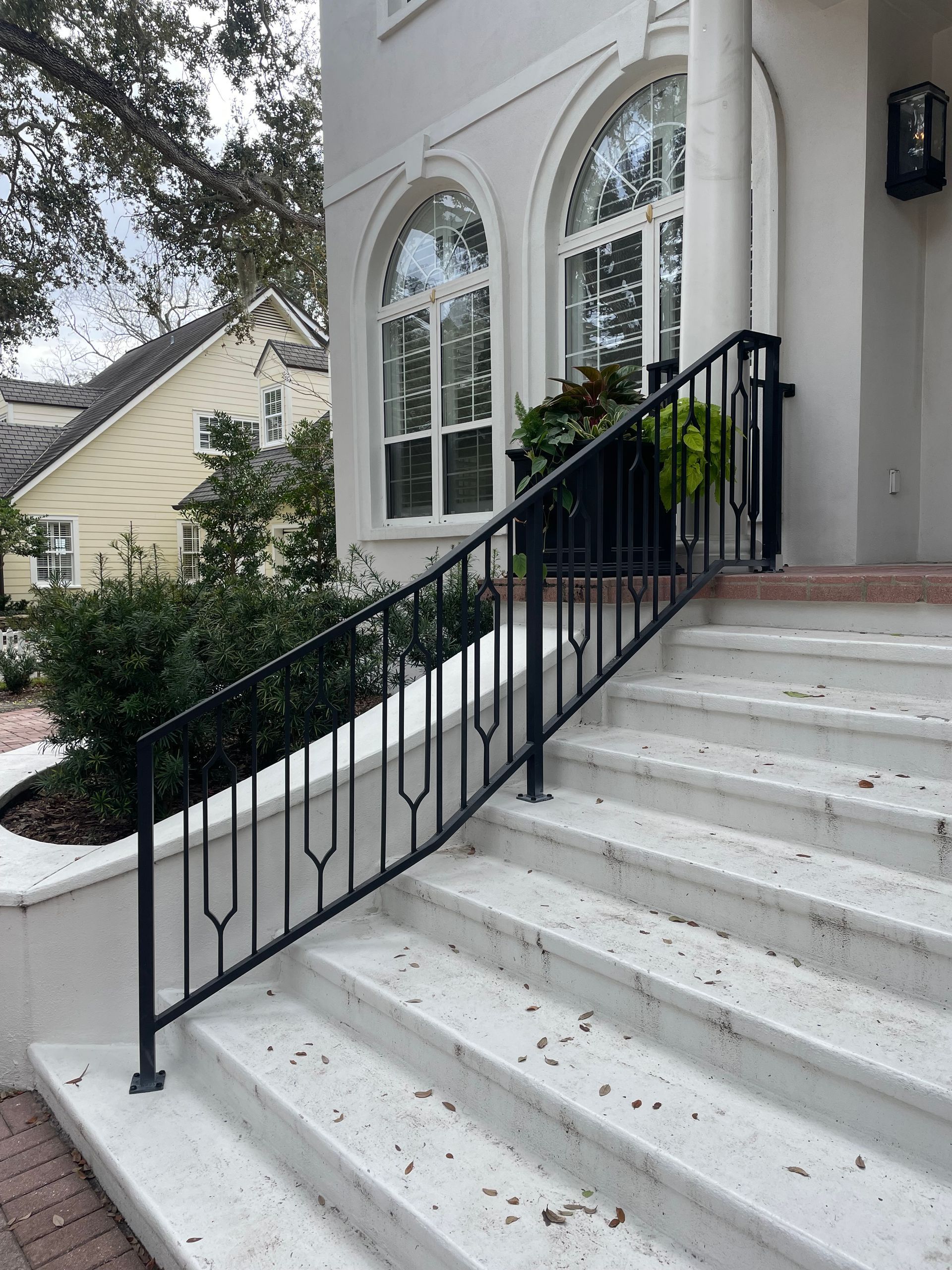 A white house with a black railing on the stairs