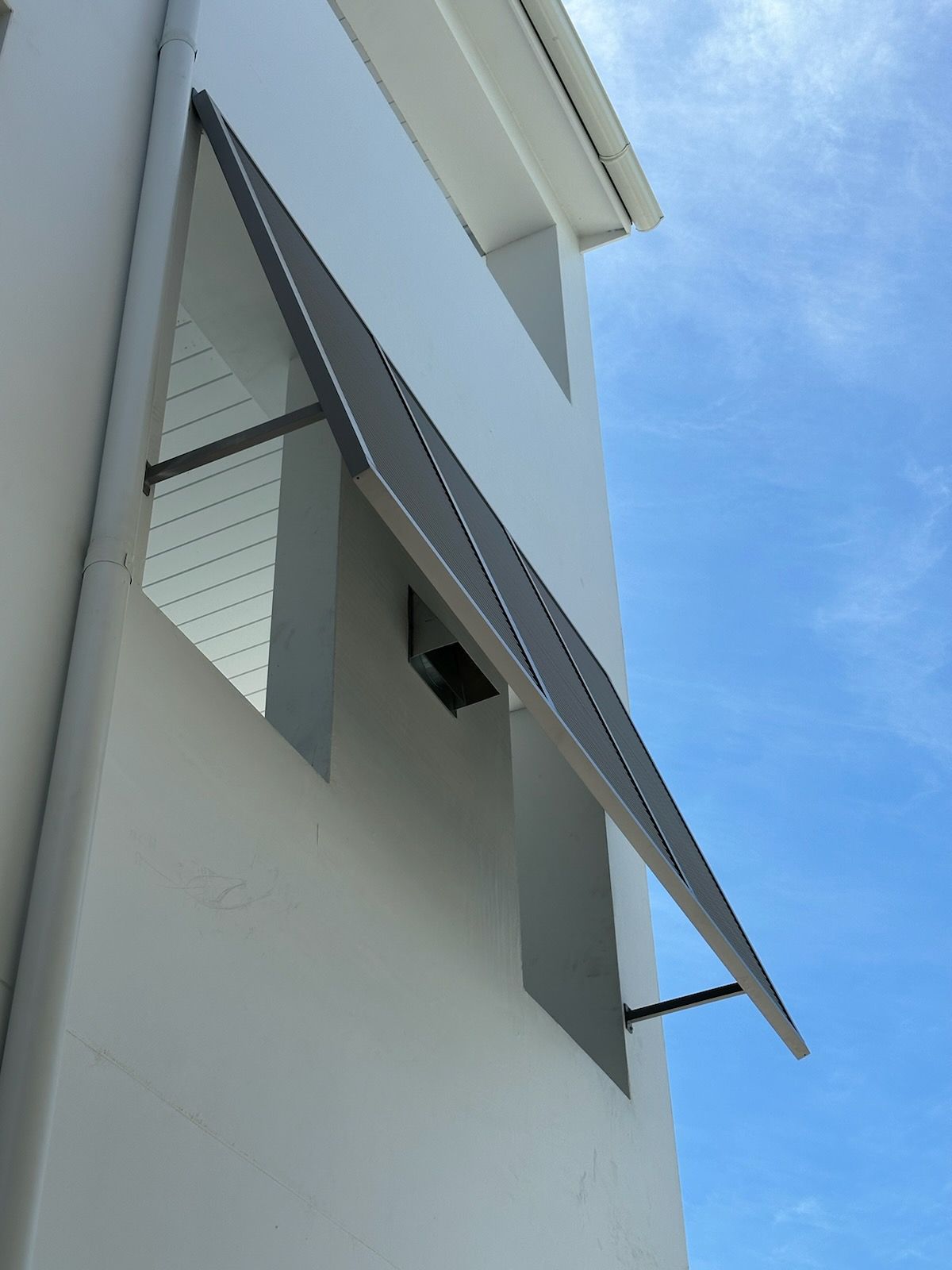 A white building with a black awning on the side of it