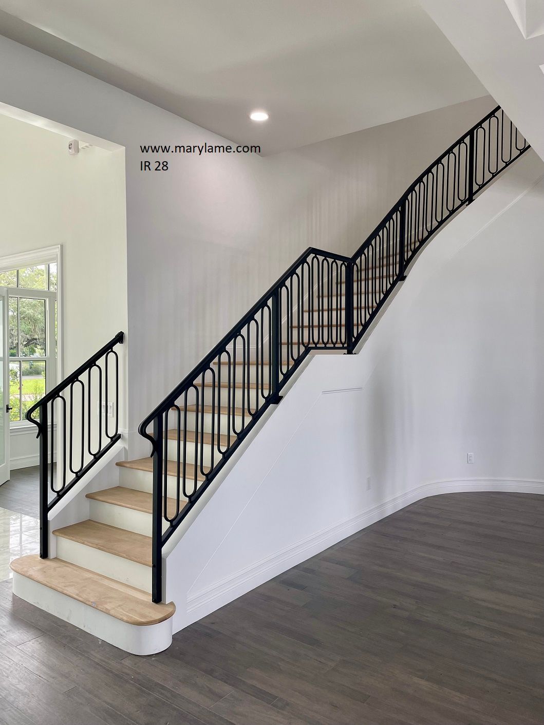 A staircase with a black railing and wooden steps in an empty room.