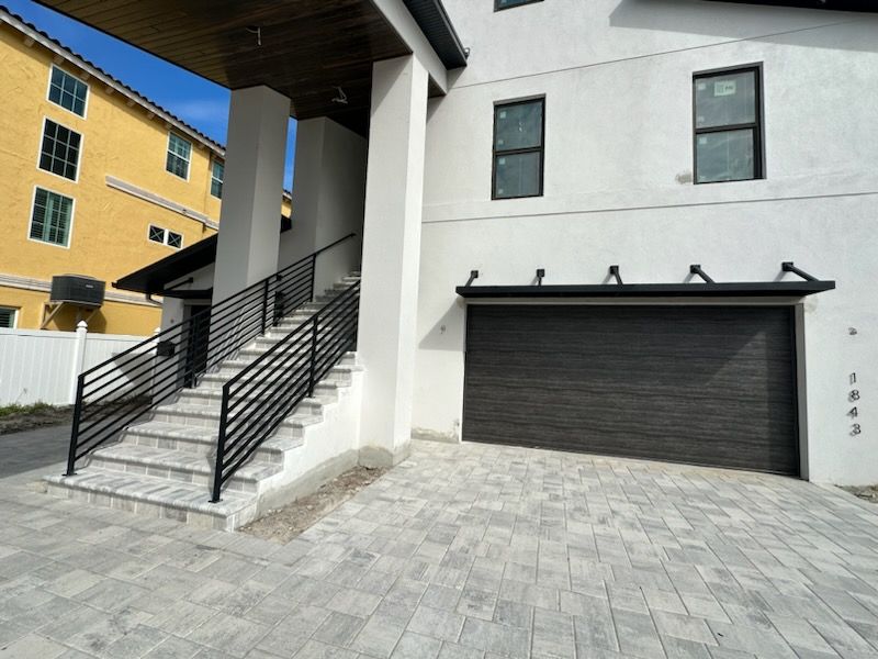 A white house with a black garage door and stairs