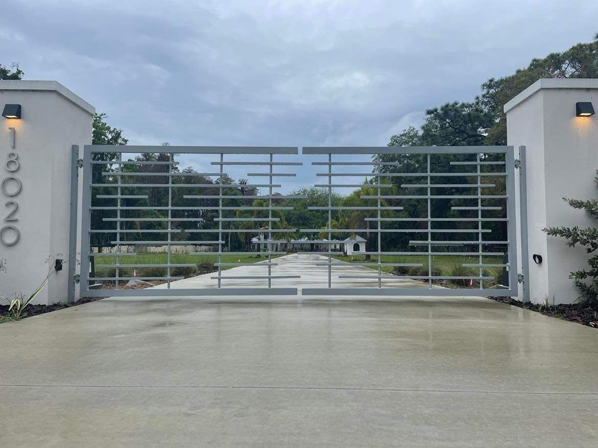 A large metal gate is sitting in the middle of a driveway.