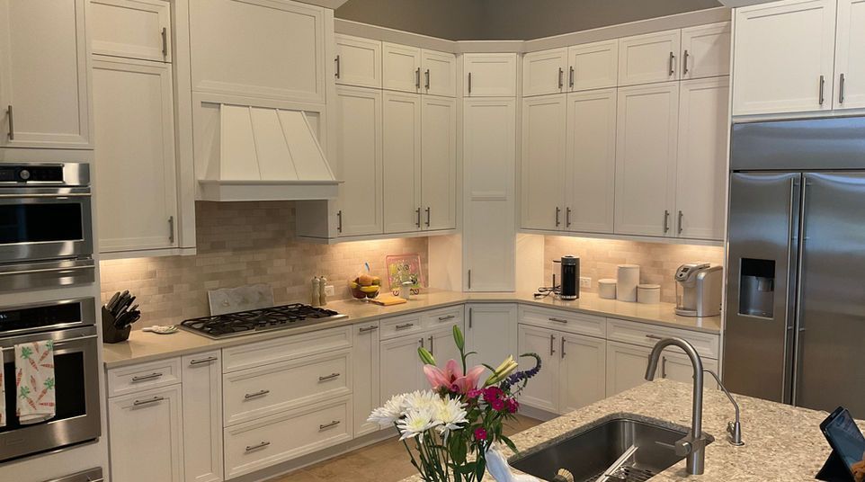 Bright white kitchen with island, stainless steel appliances, and flowers on the counter