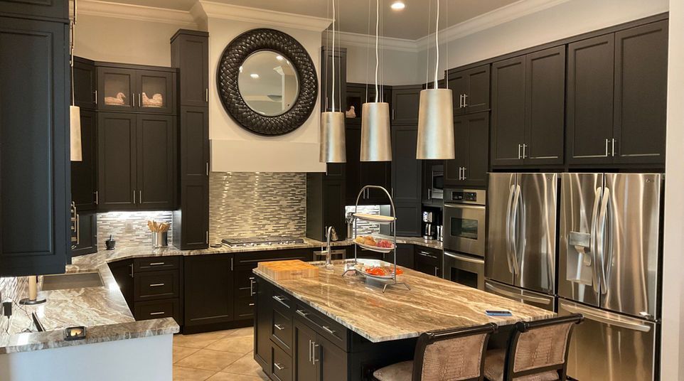 Modern kitchen with dark cabinets, granite island, stainless appliances, and pendant lights