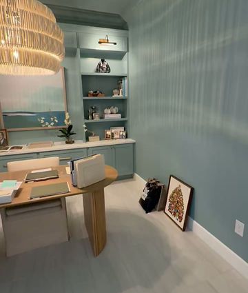 Blue dining room with wooden table, built-in shelves, and woven pendant light