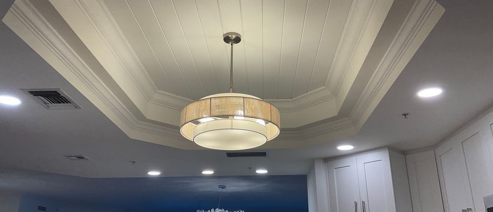 Modern ceiling with recessed lights and a round pendant chandelier in a home interior
