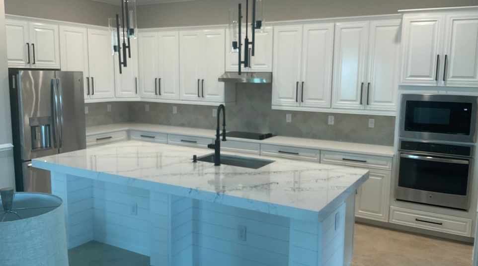 Modern white kitchen with a large island, stainless steel appliances, and gray backsplash