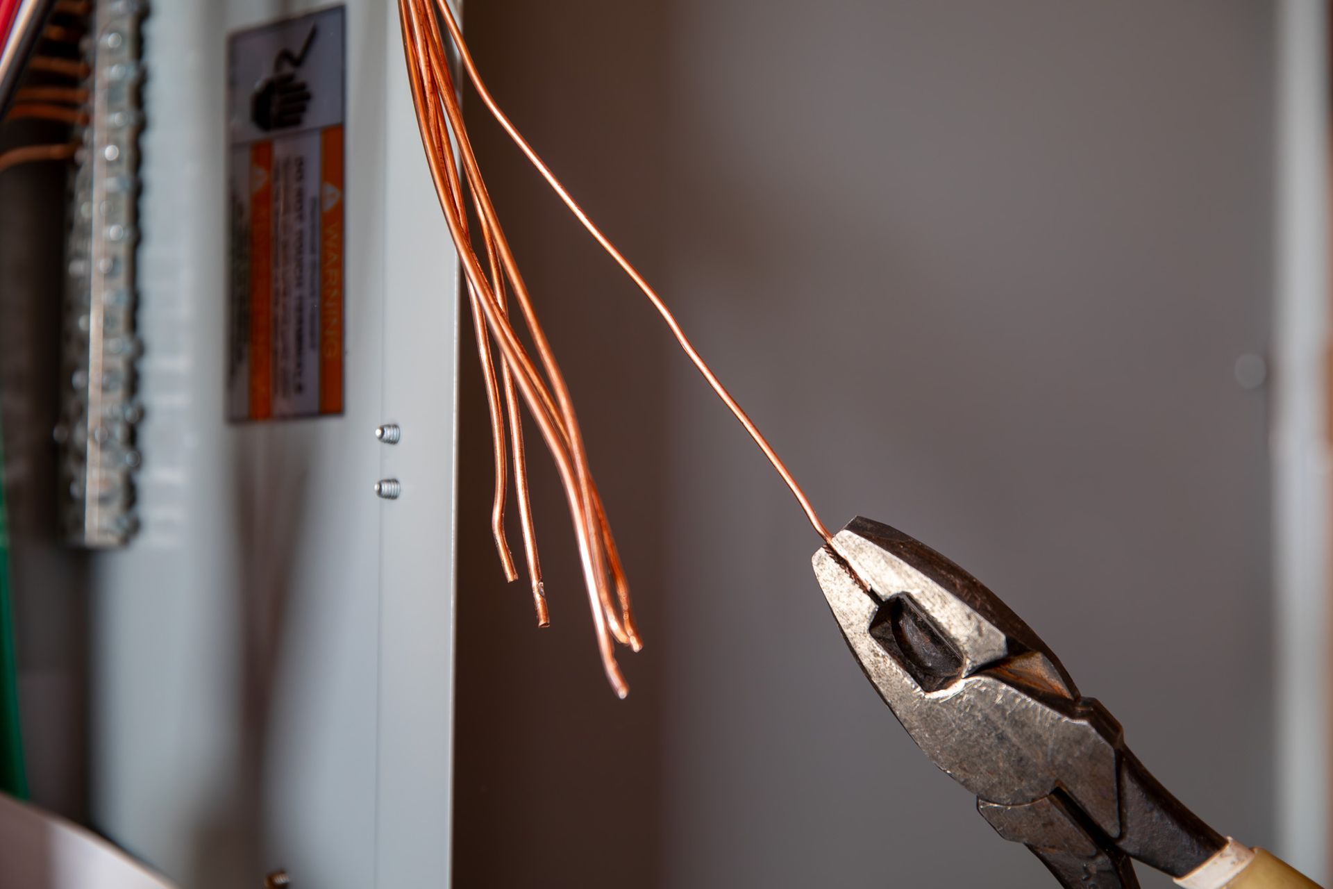 Electrician with yellow wires, standing in wooden frame of a house.