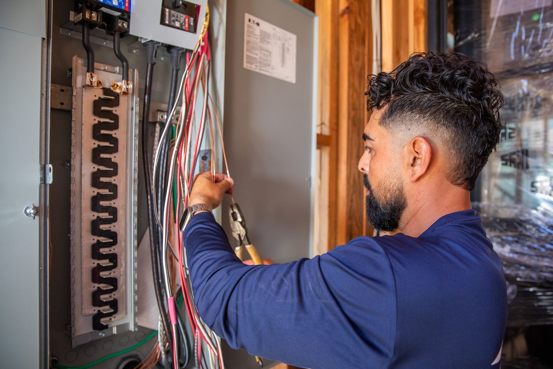Technician wiring an electrical panel with multicolored cables in a utility room