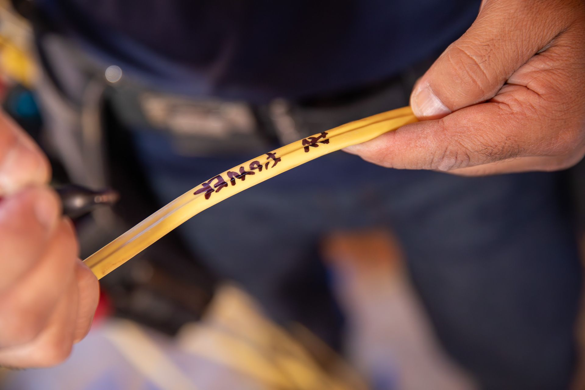 Person labeling electrical wires inside an electrical panel with a marker.