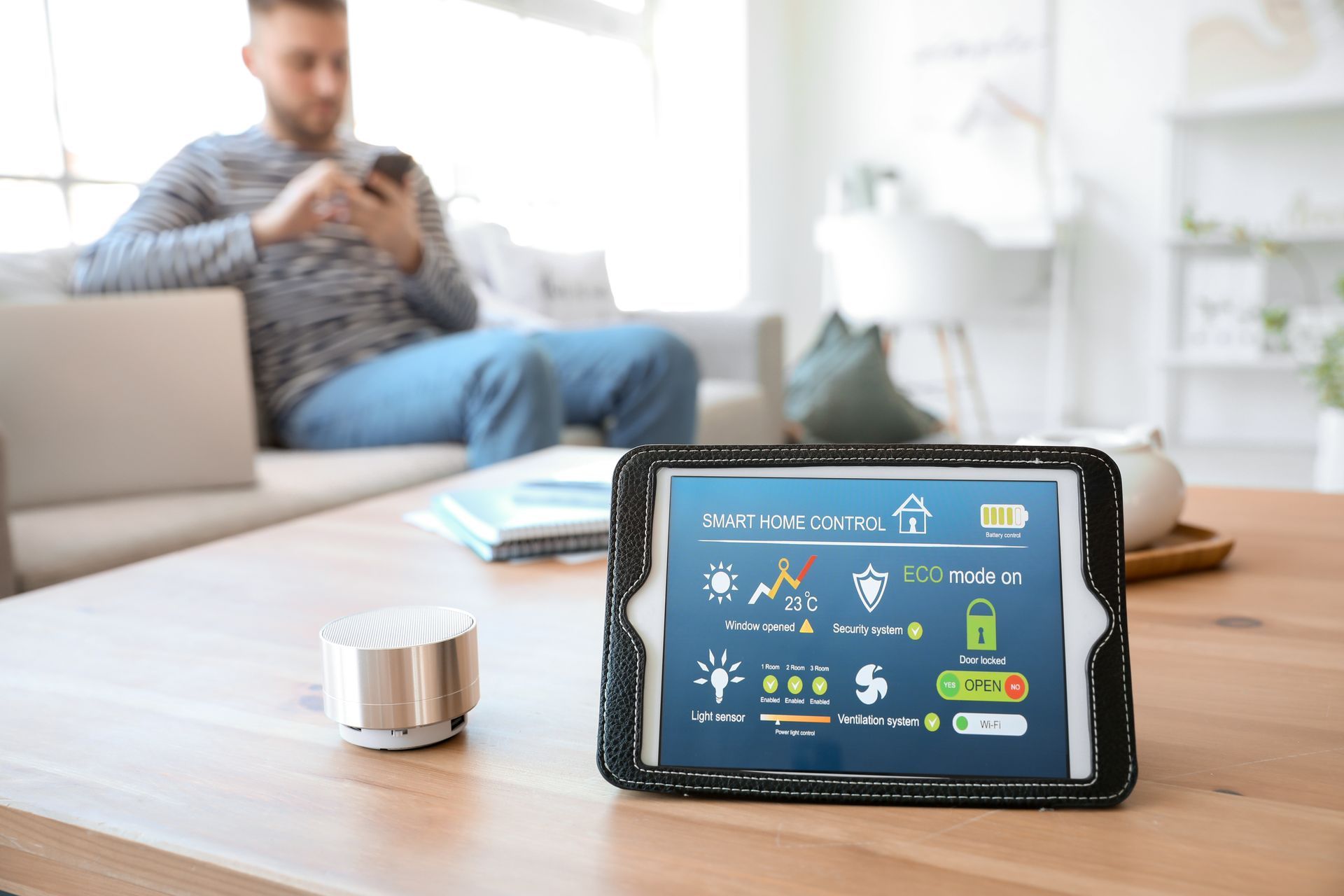 Smartphone on desk showing home dashboard, with a blurred person using a phone in the background.