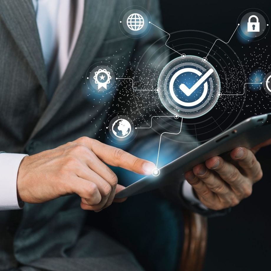 Businessman using tablet with digital quality assurance icons.