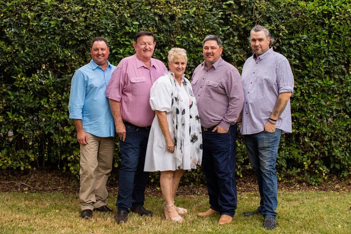 The Land Family posing for a picture in front of a bush.
