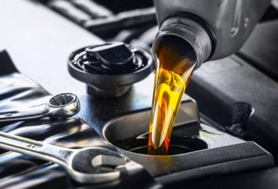 Motor oil pouring into an engine through a funnel, with car tools nearby