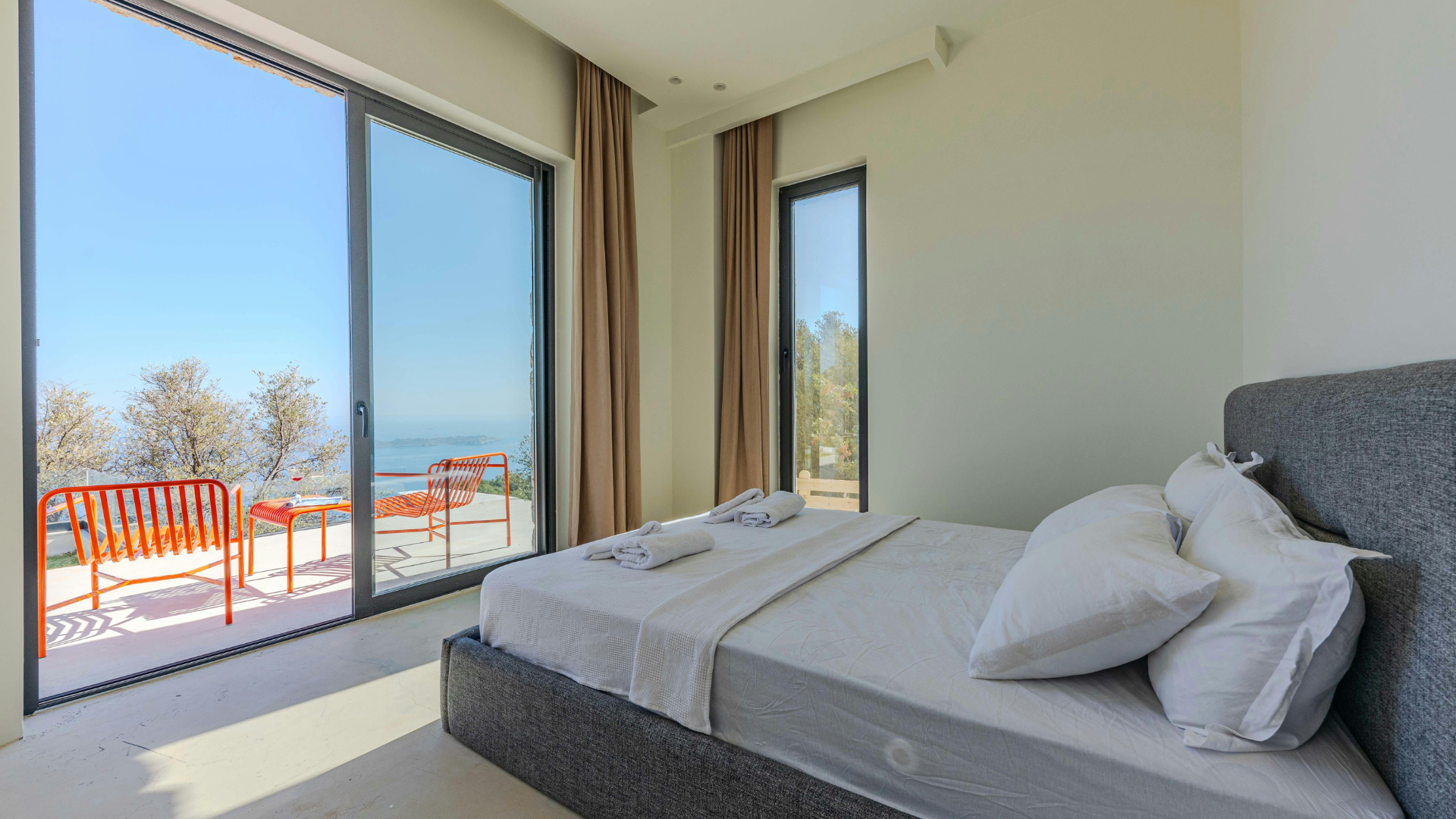 Bright bedroom with large ocean-view windows and a neatly made bed.