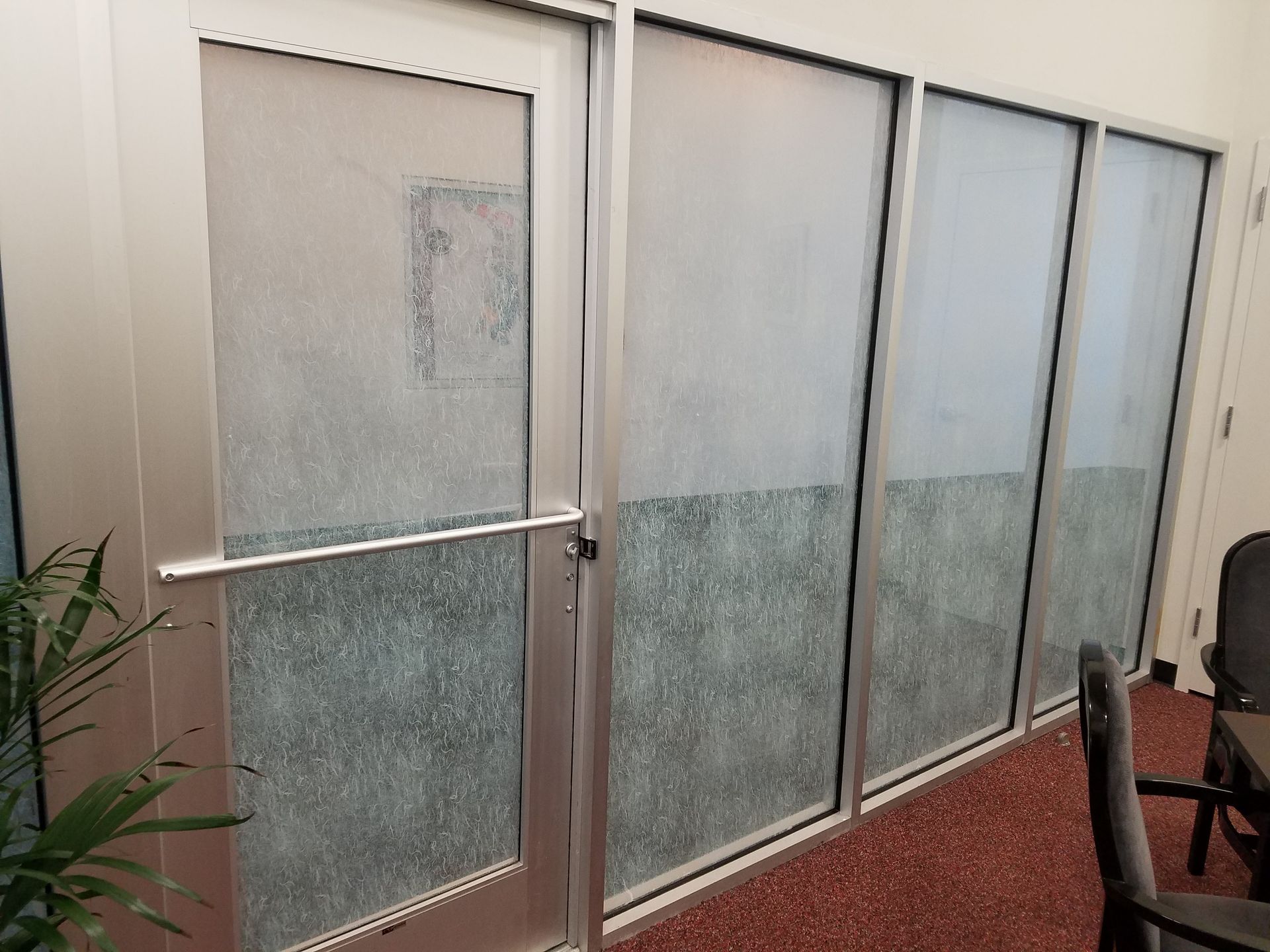 Frosted glass sliding doors in an indoor hallway with a metal handle and carpeted floor.