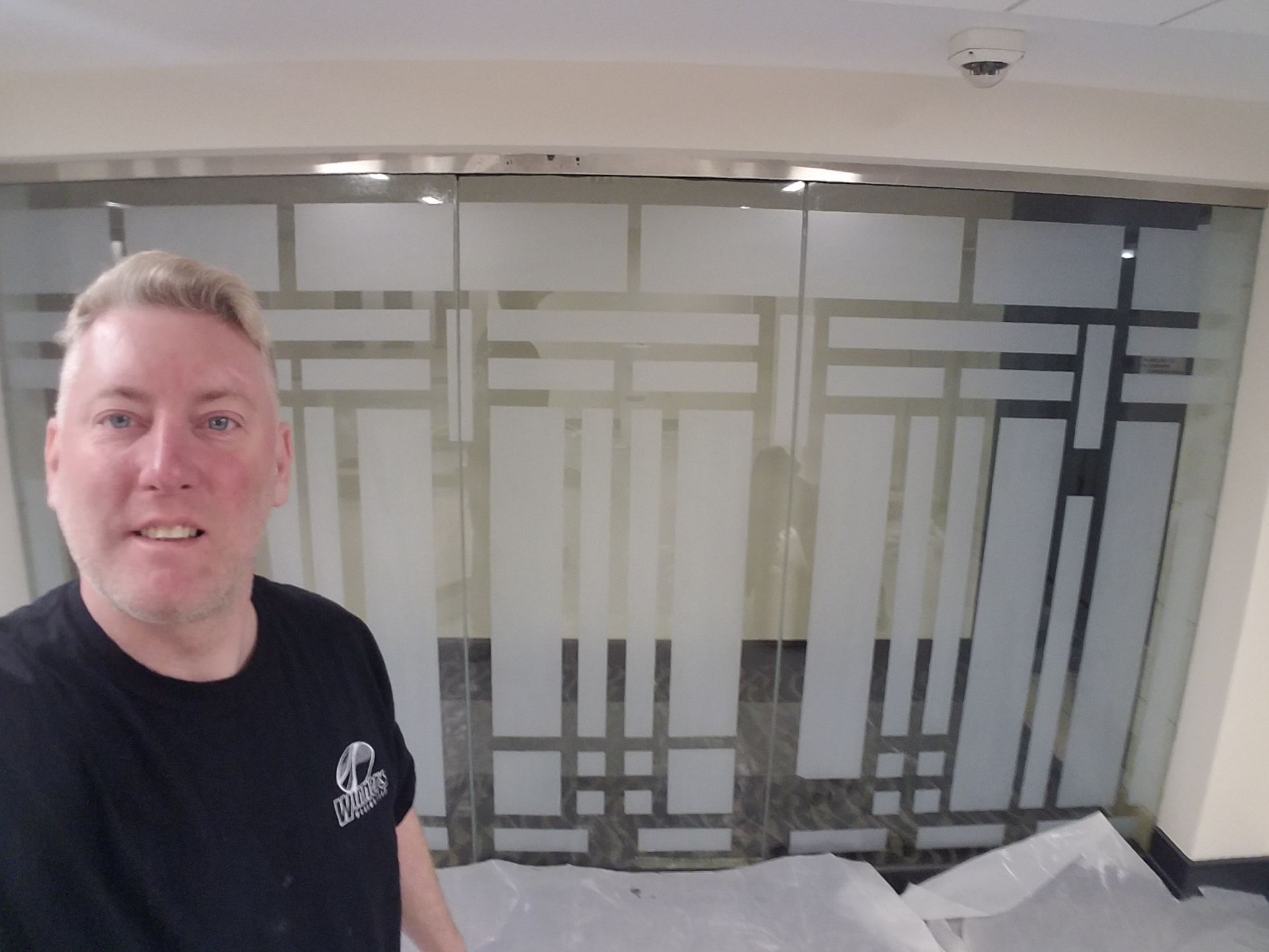 Man standing in a room with frosted glass wall panels and construction debris on the floor