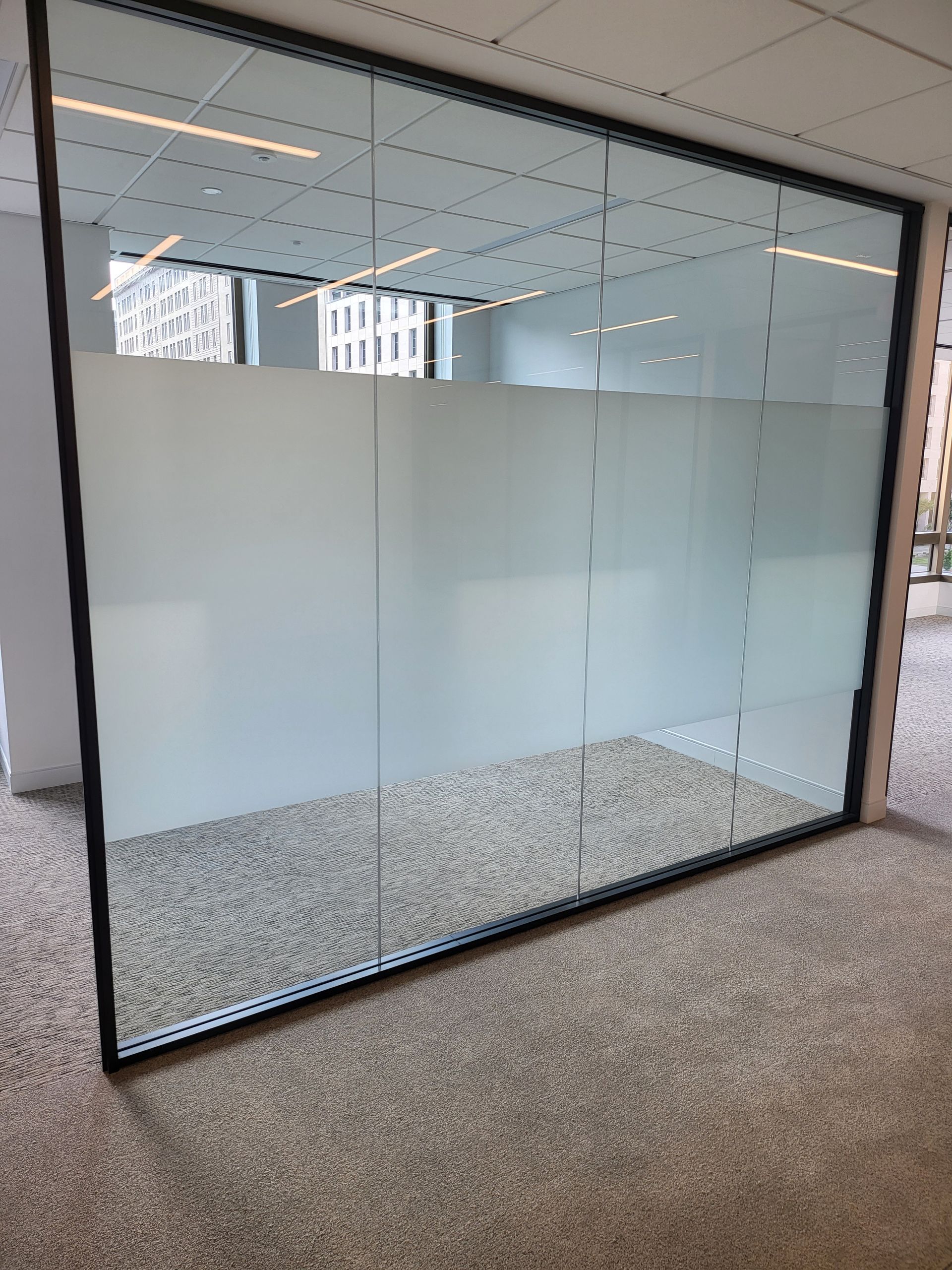 Frosted glass conference room wall with clear top panels and speckled flooring