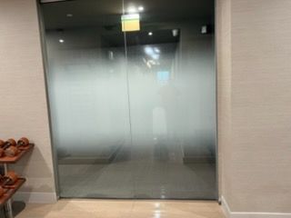 Frosted glass double doors in a hallway entrance with beige walls and a shoe rack on the left