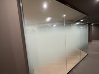 Frosted glass office partition with a reflective corner wall in a modern hallway