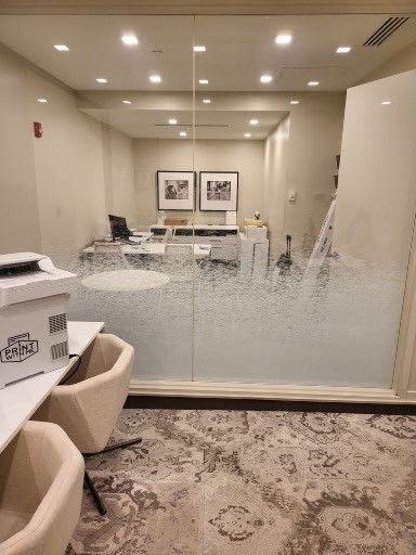 Office conference room with frosted glass partition, chairs, desk, and ceiling lights