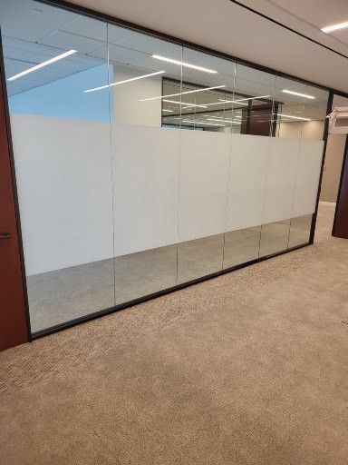 Glass office partition wall with white frosted panels in a carpeted hallway