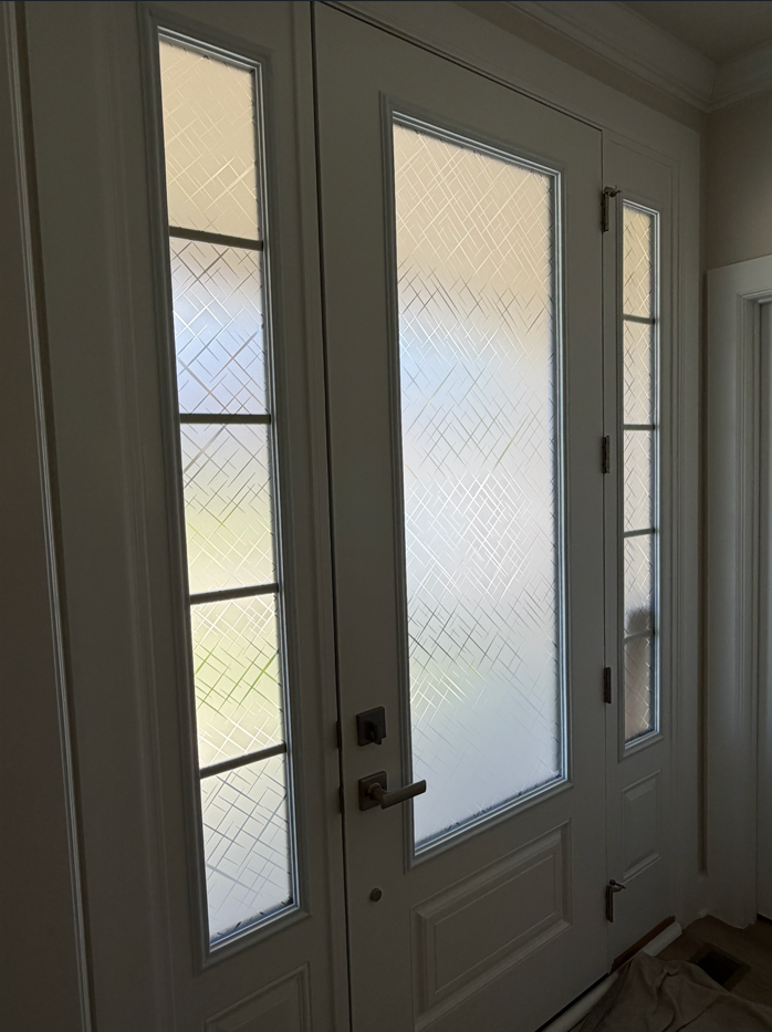 Front entry with white door and frosted glass sidelights in a softly lit hallway