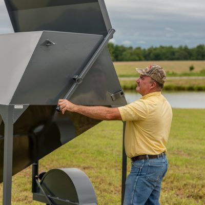 man opening top lid on gray feed trailer