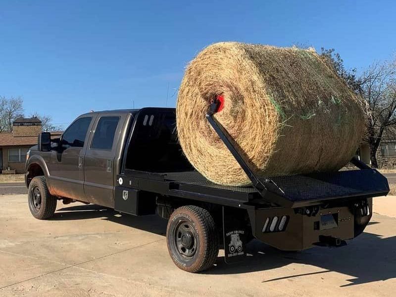 truck with arm bed lifting round bale of hay