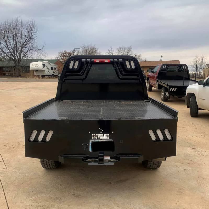 a black truck with a flat bed is parked in a parking lot